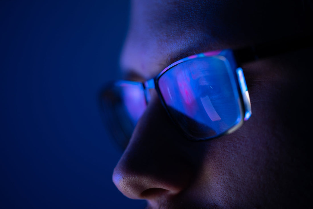 A man with glasses looking at a computer screen at night